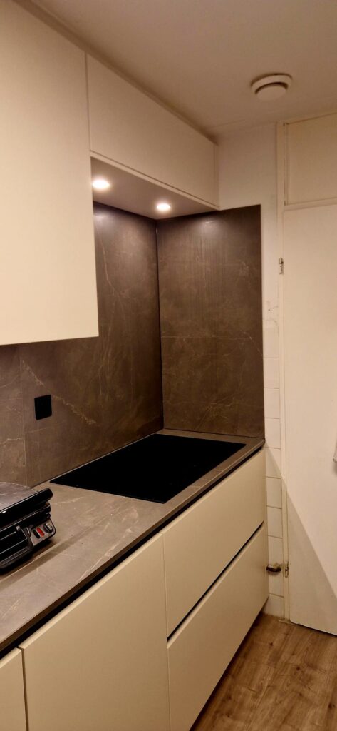 Strakke keuken in Beverwijk met lichte fronten en donkere achterwand inclusief inductiekookplaat